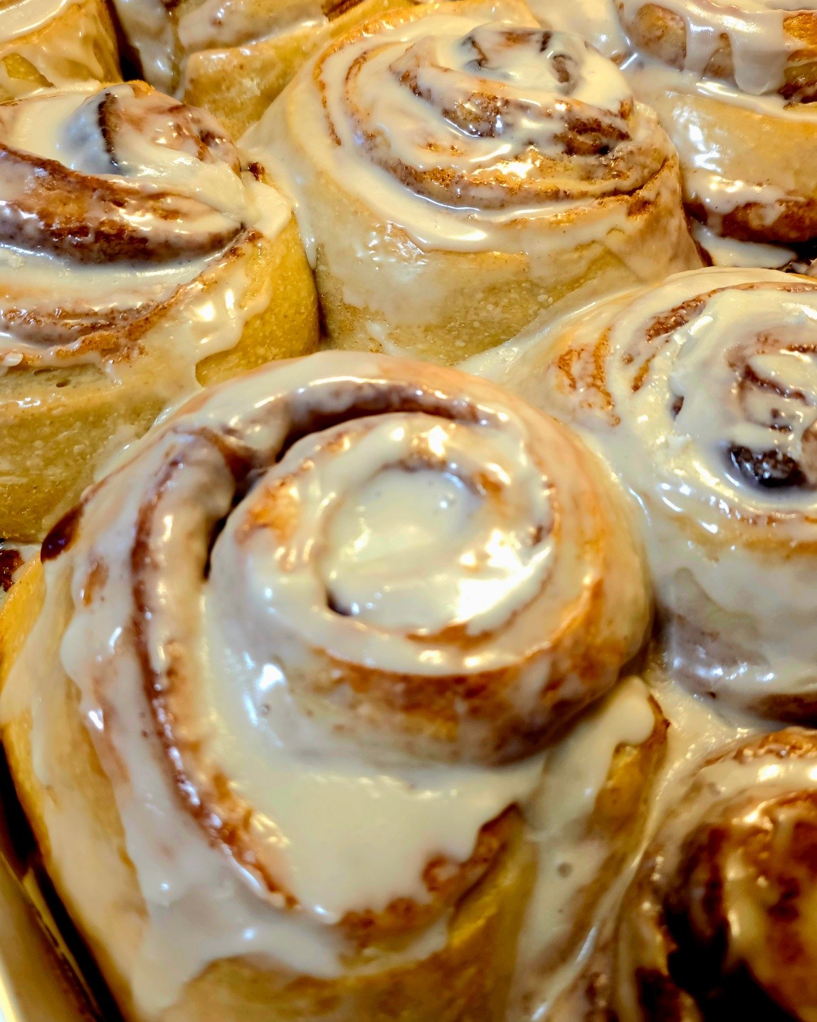 A pan of warm cinnamon rolls covered in cream cheese glaze