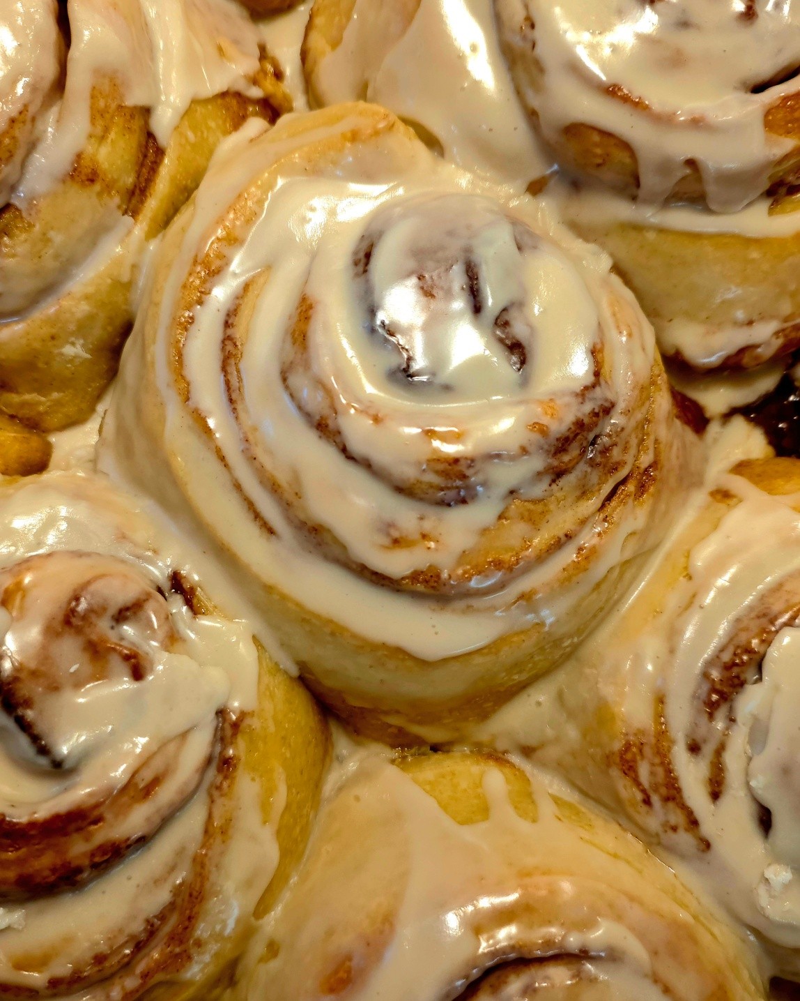 Multiple cinnamon rolls glazed in cream cheese frosting