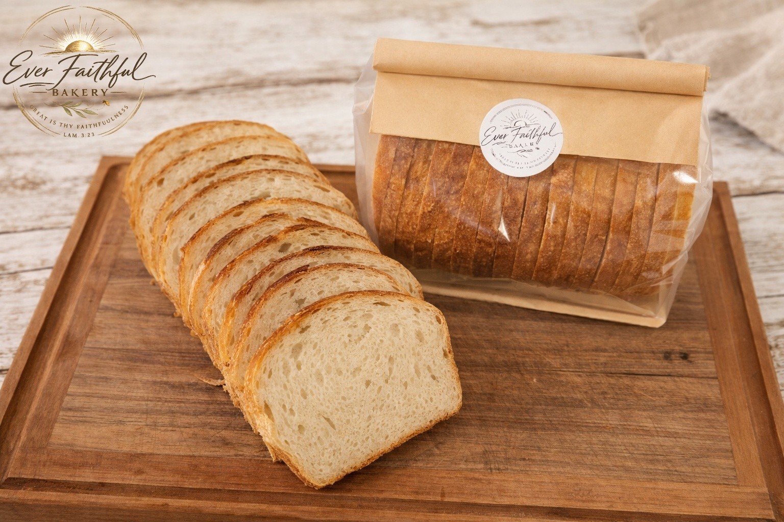 Sliced sourdough sandwich loaf next to a packaged loaf with the bakery sticker